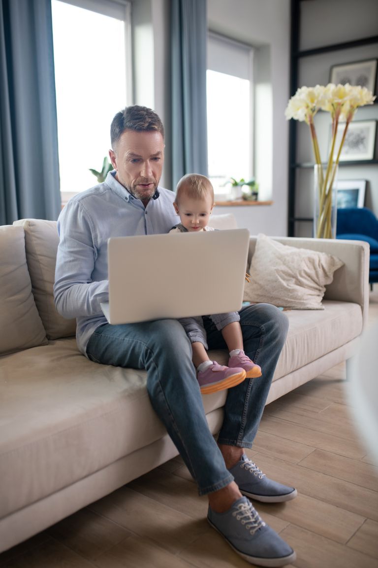 Mature father working on laptop, representing busy family manager juggling responsibilities